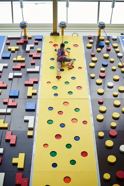 Sportswoman on the top of the wall in rock-climbing center