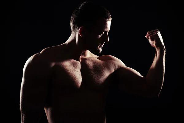 Close-up silhouette of muscular bare-chested guy showing biceps — Stock Photo, Image