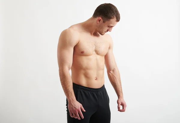 Homem muscular sobre fundo branco olhando para baixo em sua mão — Fotografia de Stock