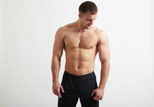 Muskulöser Mann vor weißem Hintergrund blickt nach unten — Stockfoto
