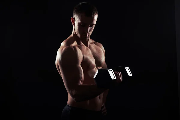Muž s činka je prohýbání bicepsy na černém pozadí — Stock fotografie