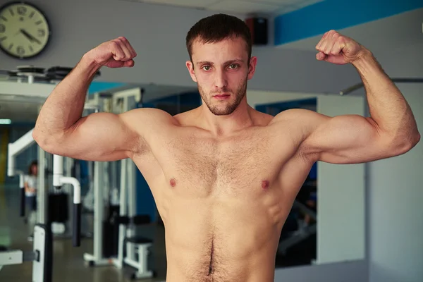 Młody człowiek mięśni, pokazując jego ciało dobrze wyszkolonych w siłowni — Zdjęcie stockowe