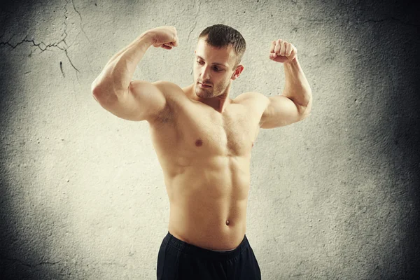 Sportovní rozhalenou muž ukazuje bicepsy na obou ramenech — Stock fotografie