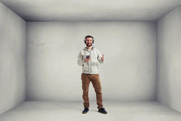 Glimlachende man hoofdtelefoon weergegeven: een duim omhoog gebaar — Stockfoto