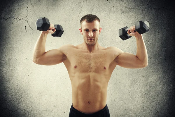 Athletic bare-chested man lifting dumbbells — Stock Photo, Image