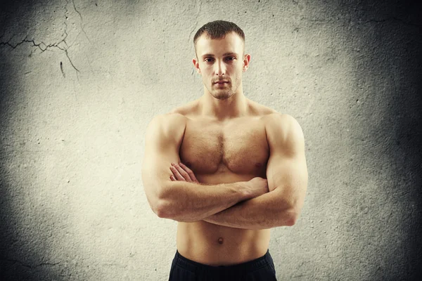 Handsome man with crossed arms over cracked wall — Stock Photo, Image