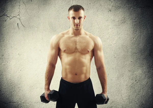 Muskulöser Mann über Betonwand mit Hanteln — Stockfoto