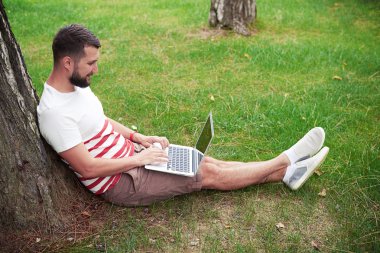 Young bearded man with laptop in the garden