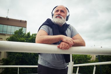 Kulaklık şık yaşlı adam handhold eğilerek ve u seyir