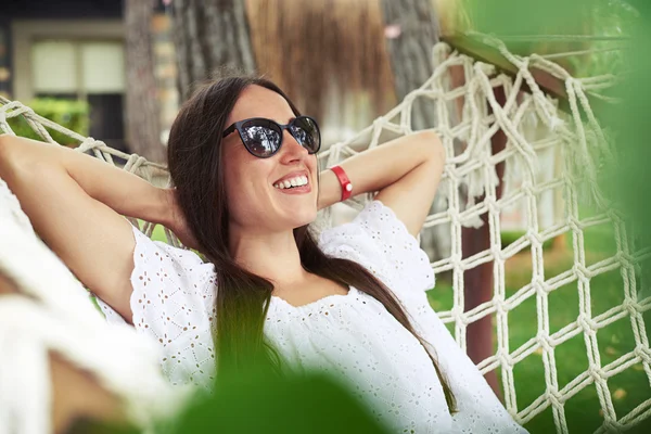 Primo piano di attraente giovane donna in occhiali da sole sdraiata in amaca — Foto Stock