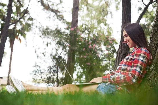 Junge Frau tippt an Sommertagen auf Laptop im Garten — Stockfoto