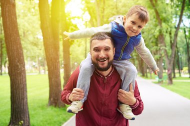  Baba güneşli bir günde parkta omuzlarında küçük oğlu sürme 
