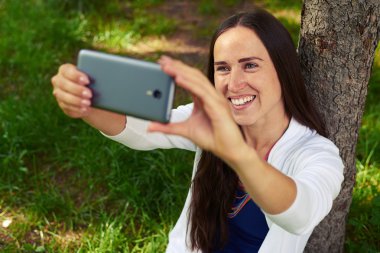  Ağacın altında dinlenen ve parkta selfie çeken gülümseyen bayan