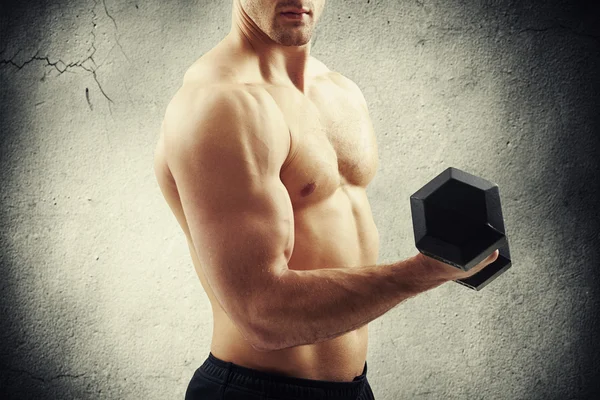 Närbild av muskulös manlig torso med hantel över betong Wal — Stockfoto