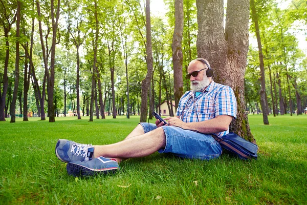 Ağacın altında oturan şık giysiler içinde yaşlı adam ve liste — Stok fotoğraf