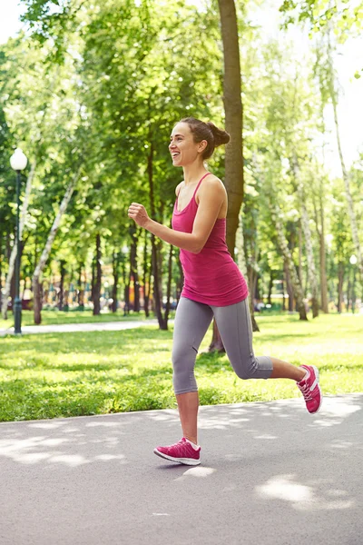 Půvabná žena v pouplavý sportovním oblečení s joggingsem v parku — Stock fotografie