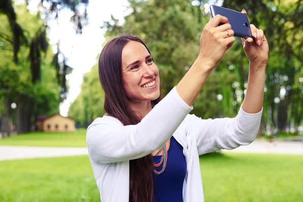 Piękna kobieta uśmiechając się do aparatu, aby zrobić selfie w p — Zdjęcie stockowe