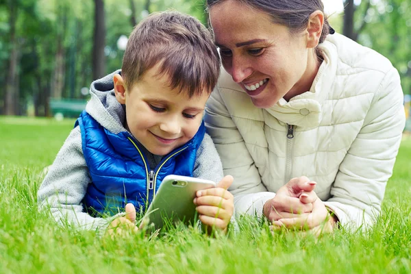 Mother and her little son enjoy nature lying on grass in park — Stock Photo, Image