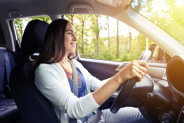 Sonriente hermosa mujer conduciendo un coche con cinturón de seguridad abrochado —  Fotos de Stock