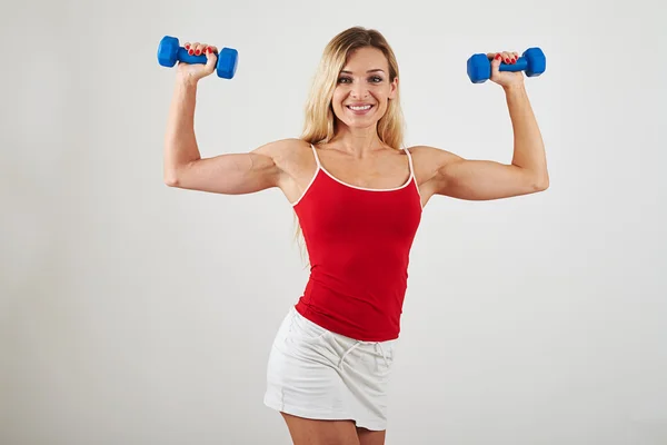 Attractive woman with athletic body holding dumbbells on white Stock Photo