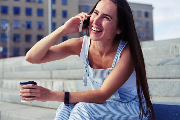 Приваблива жінка розмовляє по телефону і сміється під час сидіння — стокове фото