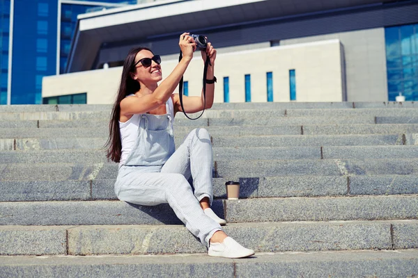 Charmante femme aux cheveux foncés assise sur les escaliers et prenant un ph — Photo