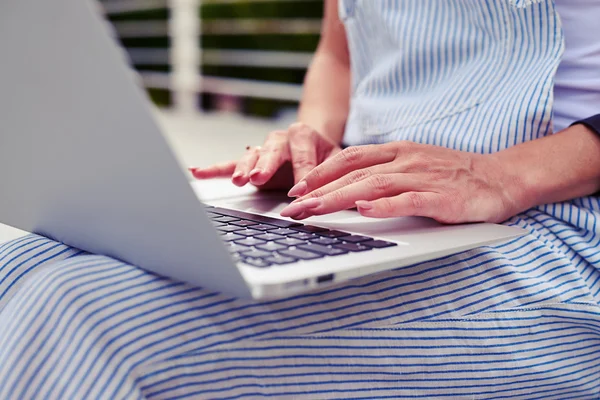 Close-up de jovem mulher em roupas casuais digitando no laptop outd — Fotografia de Stock