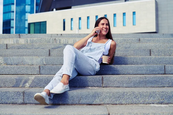 Retrato de mujer encantadora en overol descansando en las escaleras y ch — Foto de Stock