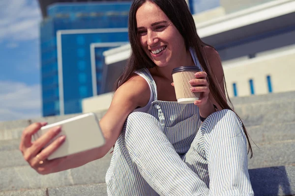 Unga leende dam med en kopp kaffe att gå pratar på — Stockfoto