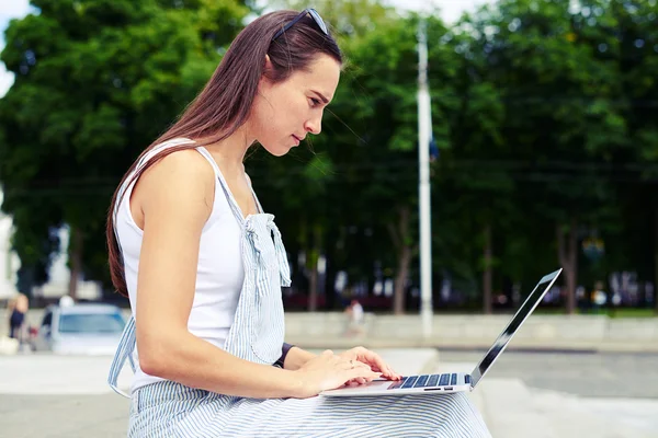 Vue latérale de la femme concentrée en salopette travaillant sur sa note — Photo