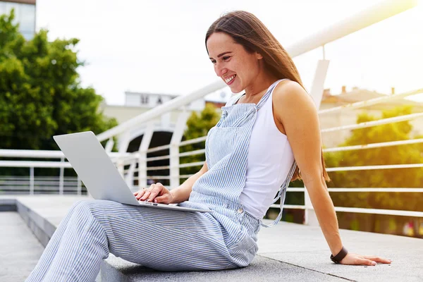 Élégante jeune femme assise sur le trottoir contre la vue sur la ville avec l — Photo