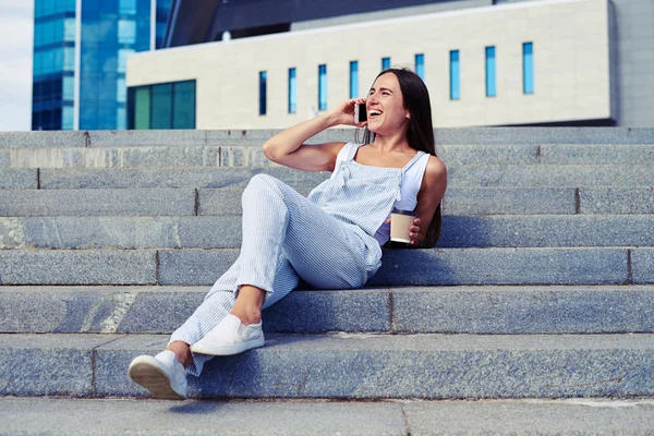 Unga leende dam med en kopp kaffe att gå pratar på — Stockfoto