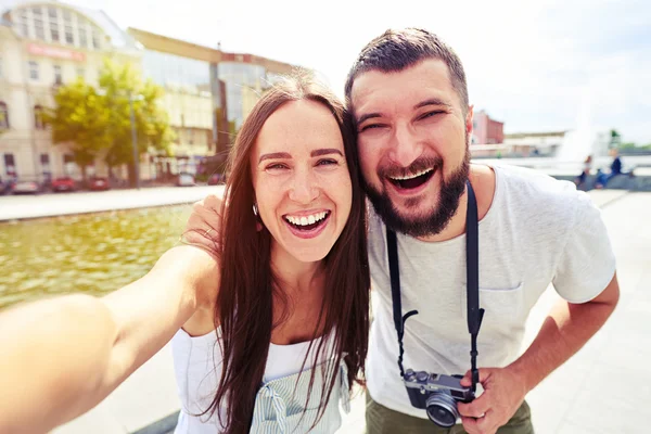 Pareja joven sonriendo sinceramente mientras hace selfie — Foto de Stock