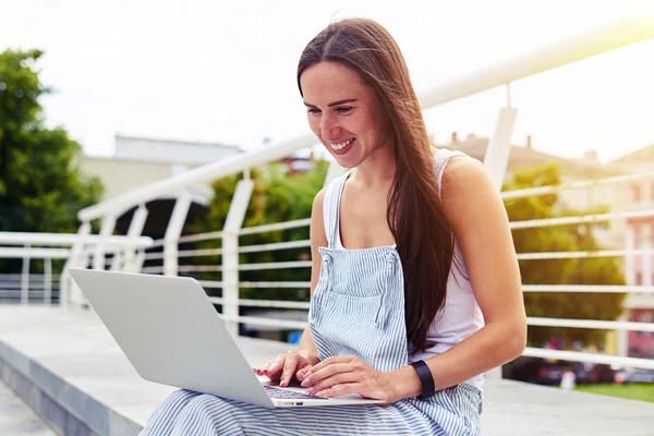 Young beautiful lady sitting on the street on sunny day and wor — Stock Photo, Image