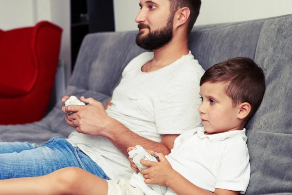 Padre e hijo se concentraron en jugar un videojuego usando joystic — Foto de Stock