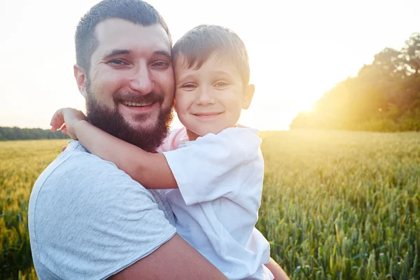 Porträt von lächelndem Vater und Sohn bei Sonnenuntergang auf dem Feld — Stockfoto