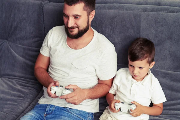 Niño pequeño dispuesto a ganar mientras juega un videojuego con su padre —  Fotos de Stock