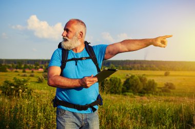 Sakallı adam sırt çantası ve veri tablet bir şeye işaret 