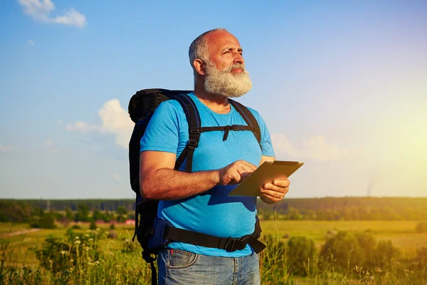 Hombre barbudo con mochila y tableta de datos contra el campo de puesta de sol b — Foto de Stock