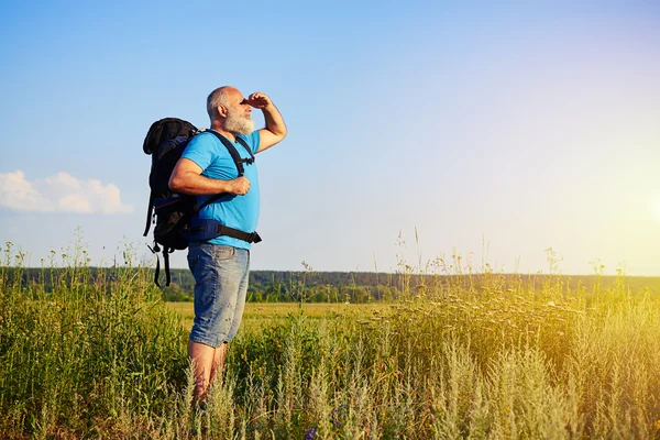 Fysiek fit leeftijd man met rugzak kijken van zonlicht — Stockfoto