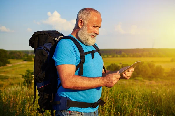 Deportivo anciano con mochila buscando algo en la tabla de datos — Foto de Stock