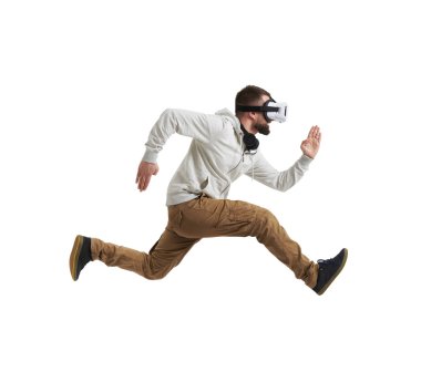 Young man in virtual reality headset in mid-air jump on white ba