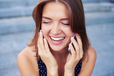 Geniş smil ile telefonda konuşan güzel kızın yakın çekim