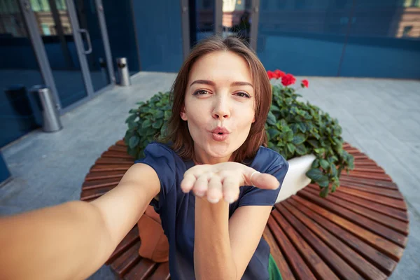 Piękna młoda kobieta dmuchanie pocałunek podczas pozowanie do selfie — Zdjęcie stockowe