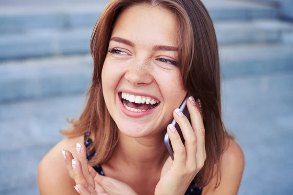 Счастливая молодая женщина смеялась, разговаривая по телефону на улице — стоковое фото