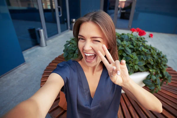 Junge fröhliche Frau zeigt v Zeichen und zwinkert, während sie eine s — Stockfoto