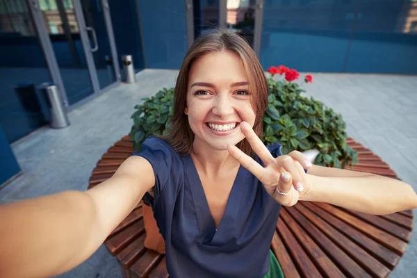 Jovem bela mulher mostrando sinal V ao fazer uma selfie — Fotografia de Stock