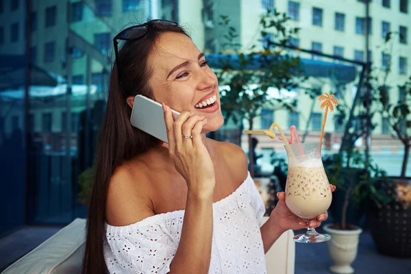 Young female with cocktail in her hand cheerfully speaking on th — Stock Photo, Image