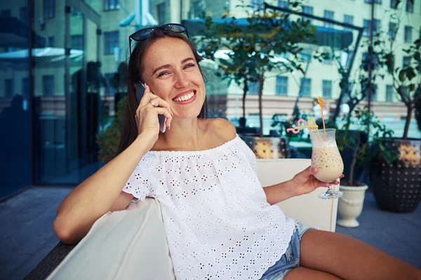 Young woman in casual clothes with cocktail talking on the phone — Stock Photo, Image