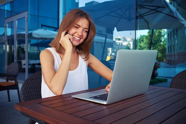 Sonriente hembra utilizando internet inalámbrico en el ordenador portátil en el café al aire libre —  Fotos de Stock